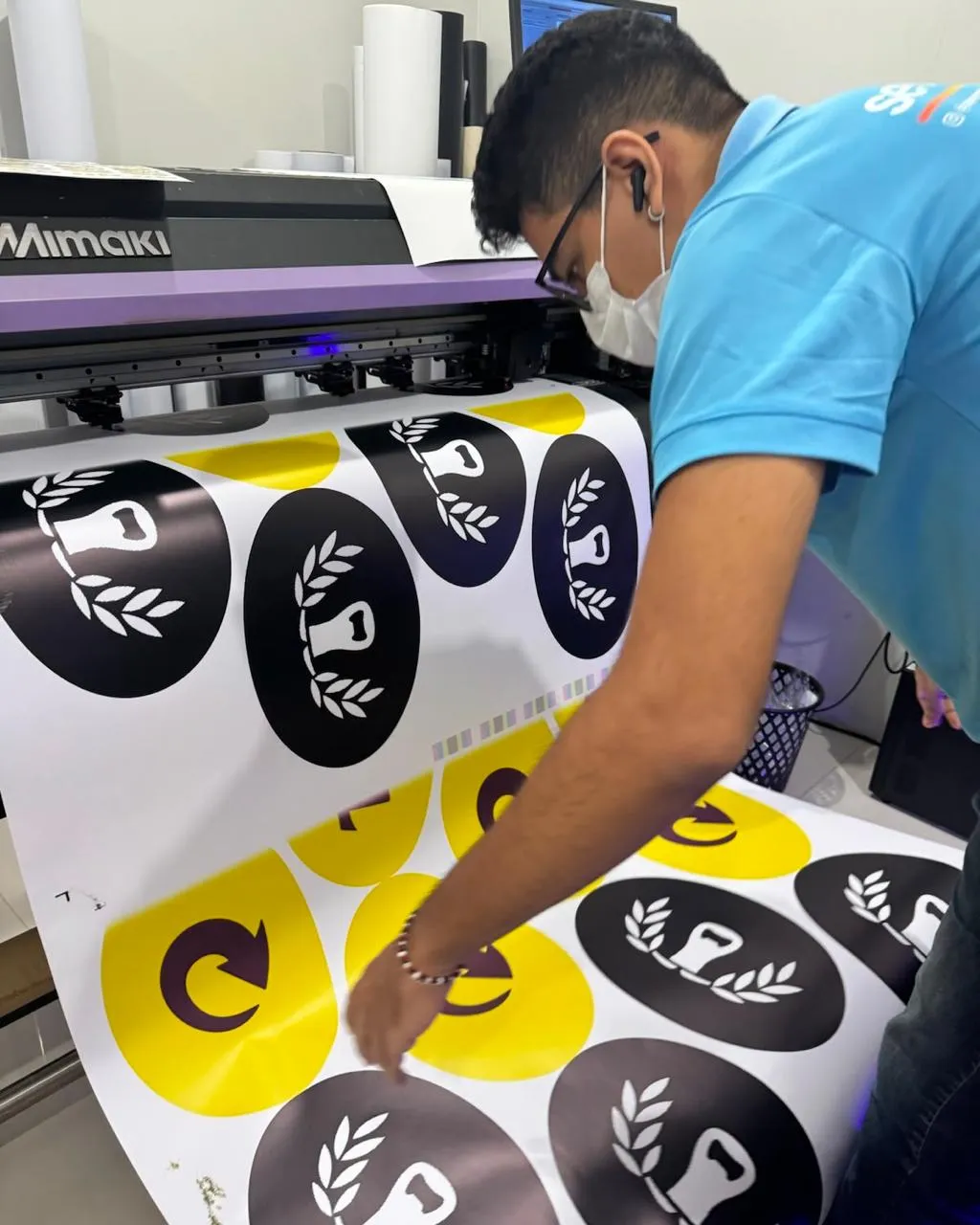 Colaborador acompanhando impressão em equipamento de grande formato Mimaki.